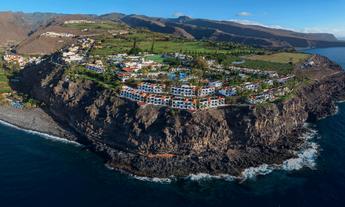 a hotel perched on cliffs with the sea and beach below