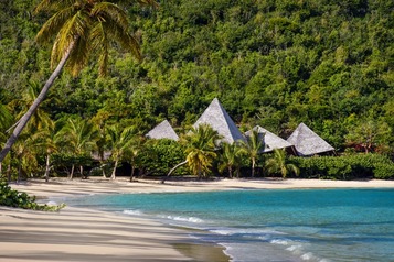 a beach in the british virgin islands with some pavilions amongst the palm trees 