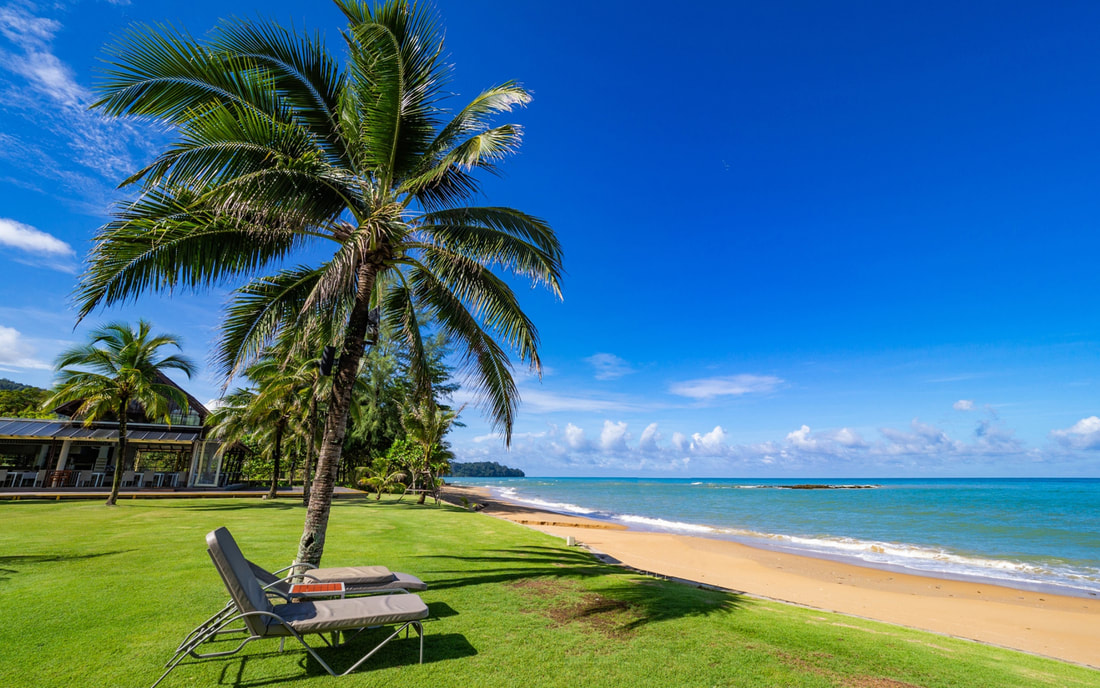 a sunlounger on grass overlooking a beach and the sea at the Sands Khao Lak