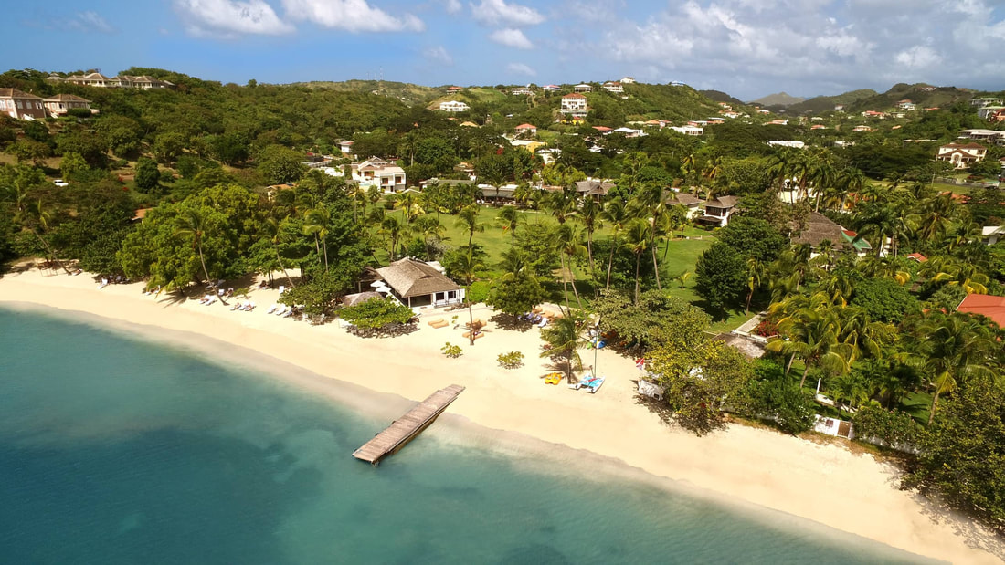 Looking down on a beach with a jetty and the Calabash Luxury Boutique Hotel