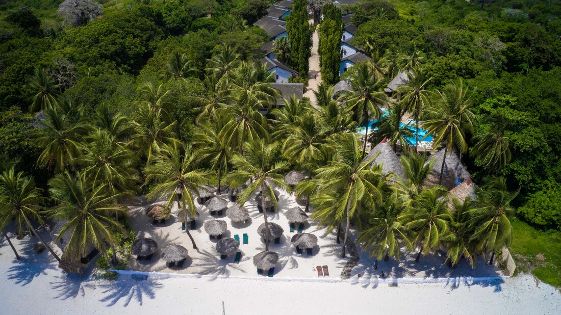looking down on a beach with a hotel amongst the trees