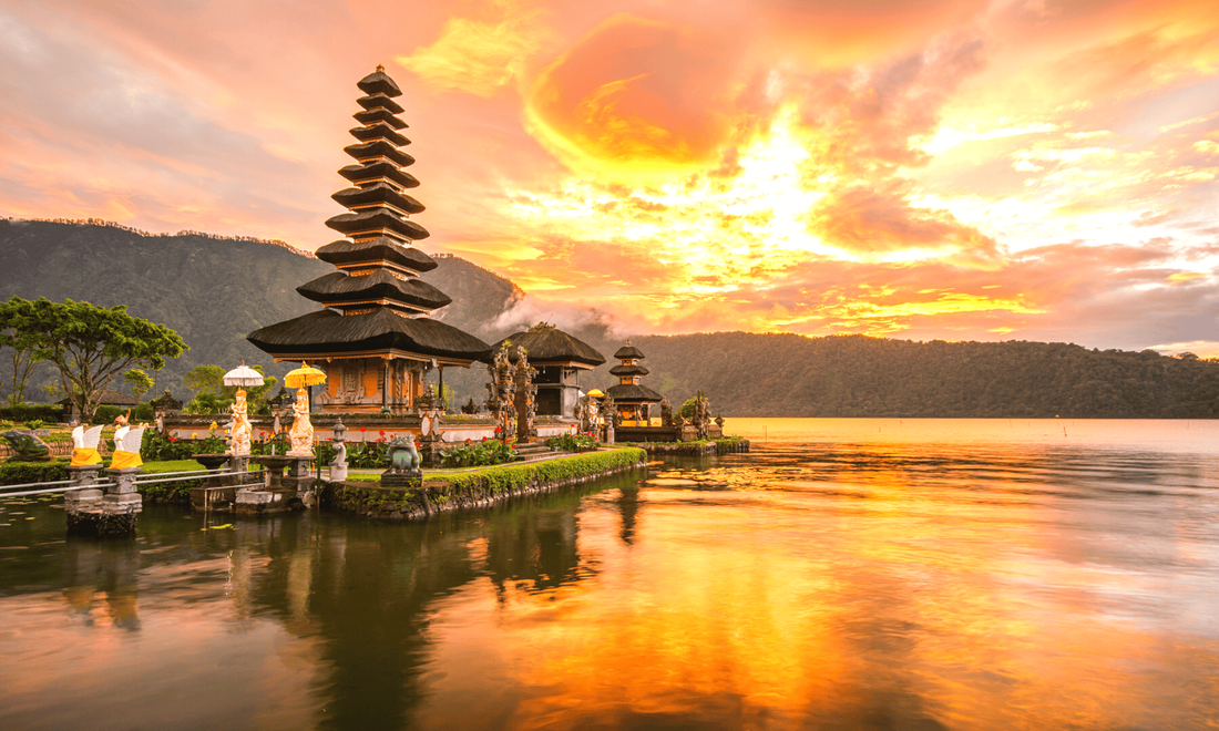 a temple on the edge of a lake at sunset