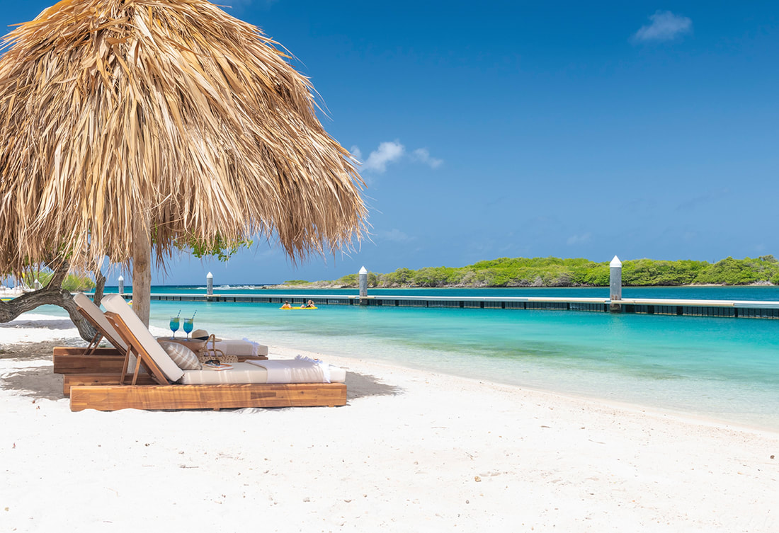 two sunloungers covered with a palm on a white sand beach at Sandals Curacao
